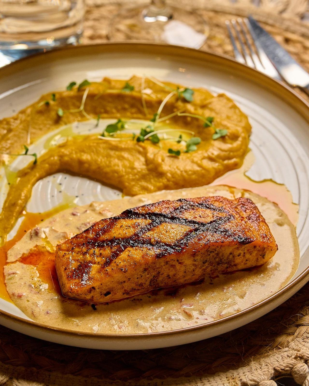 Salmón a las brasas glaseado con ajonjolí sobre vegetales salteados