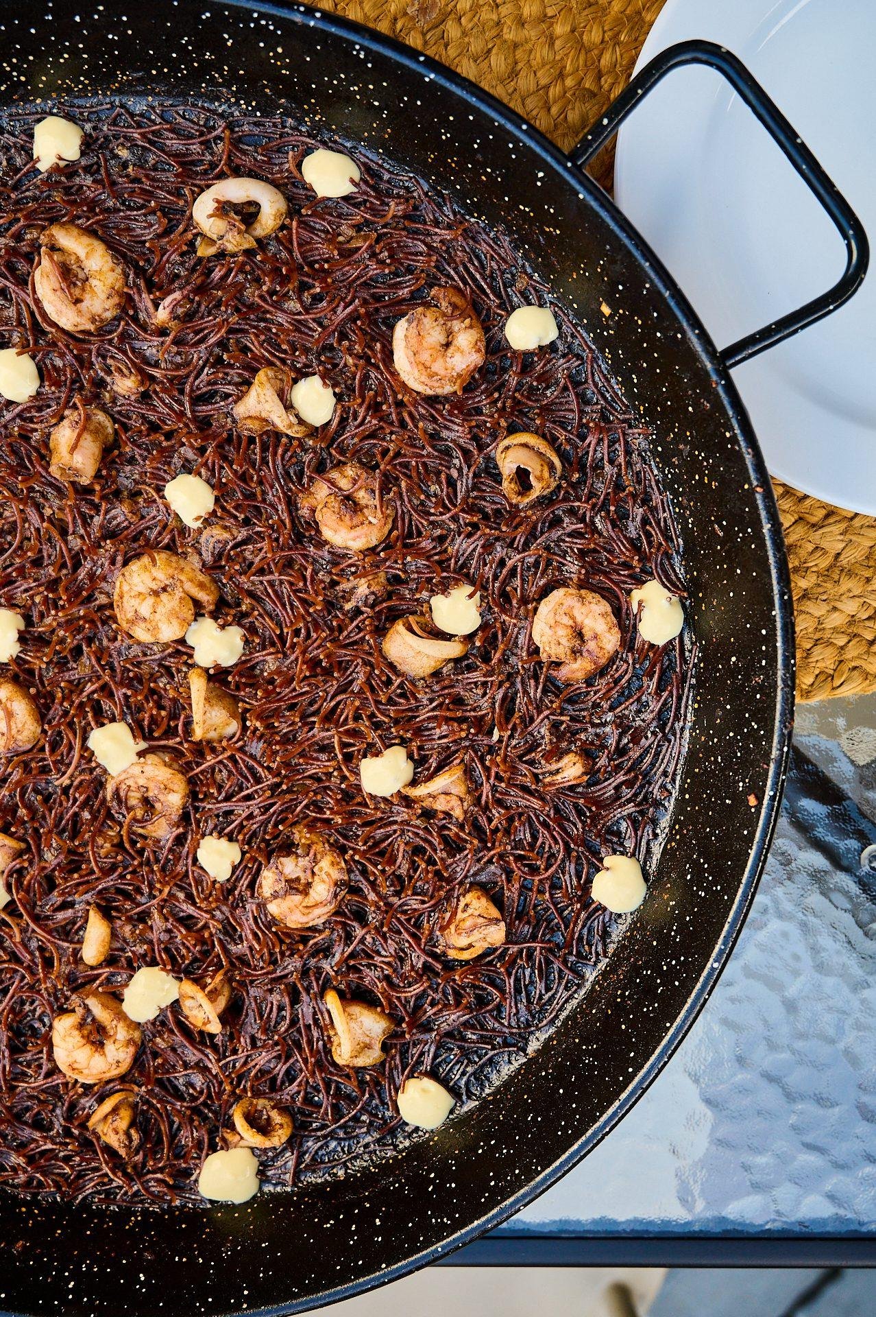 Black rice with prawns and aioli in a paella pan, Santa Rita's signature dish